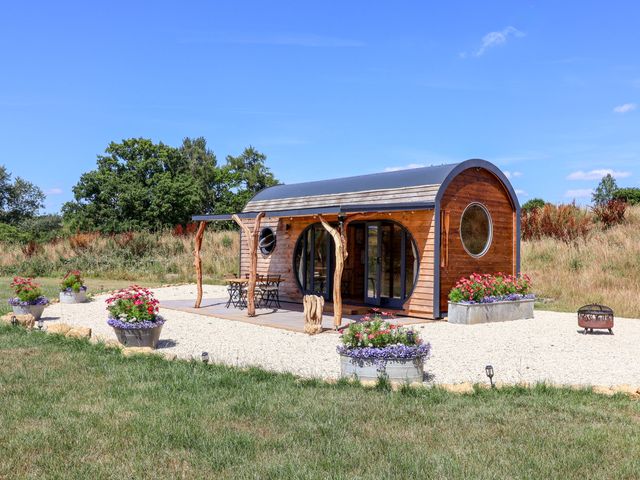 A wooden cabin with outdoor seating and flower planters at Bugley Pools Hideaway in Bugley near Gillingham