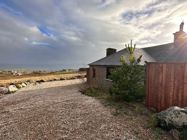 An outdoor view of a house with a gravel driveway at Cobble Stone Cottage near Leabgarrow, County Donegal