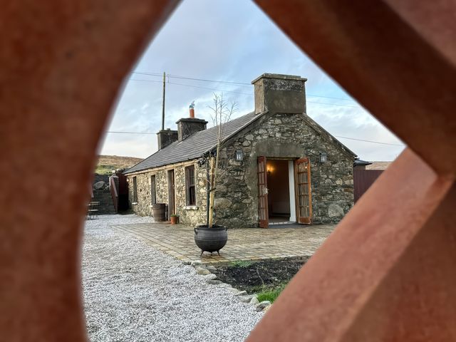 A stone cottage with open doors and gravel path at Cobble Stone Cottage near Leabgarrow, County Donegal