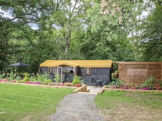An outdoor area with a cabin and chairs at Charltons Hollow Cabin in Haywards Heath