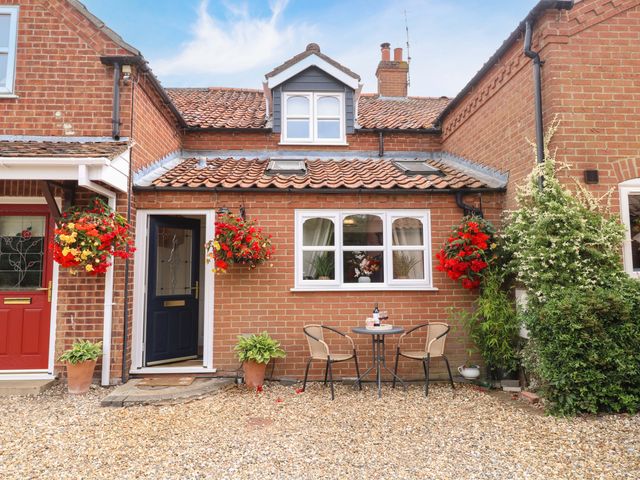 An outdoor area with a table and chairs at Honeysuckle Cottage in Swaffham