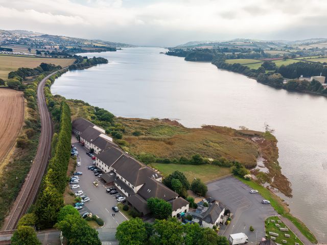 An aerial view of a river with fields and a building along its bank at Mallard in Kingsteignton