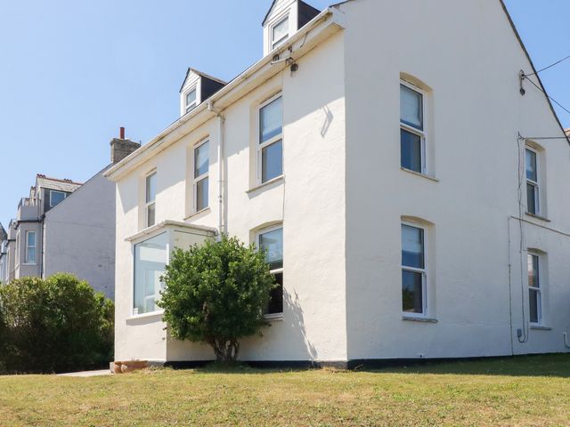 A house with windows and grass in the yard at Tregundy Farmhouse in Perranporth