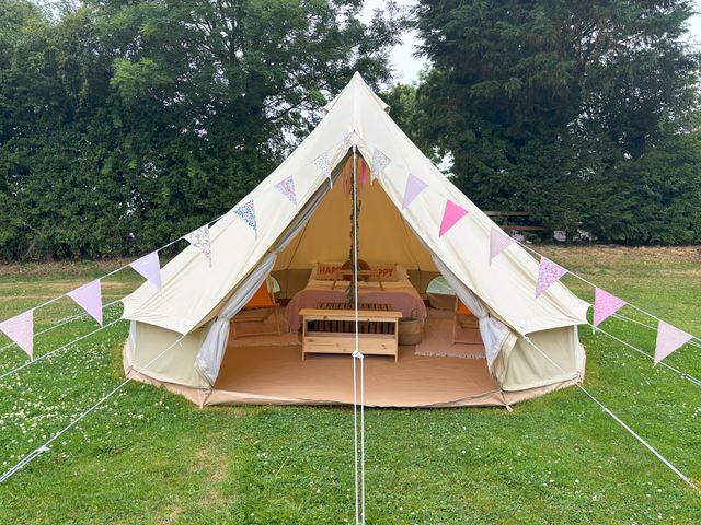 A tent with a bed and decorative bunting at Bell Tent in 