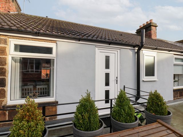 An outdoor view of a house with a door and plants at Postman’s Lodge in Great Ayton
