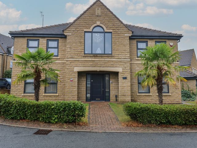 A house with palm trees and a front door at 20 Overland Crescent in Apperley Bridge