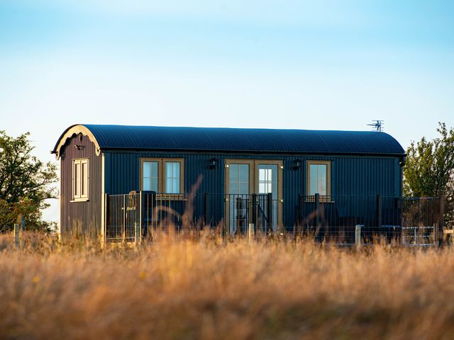A shepherd's hut with windows and a door at Head For the Hills Glamping - Skylark Shepherd's Hut
