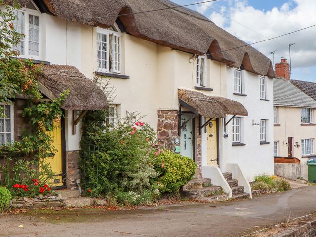 A thatched roof house with yellow and green doors at Cosy Nook in South Molton
