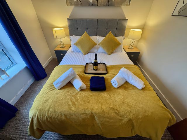 A bedroom with a bed, bedside table, and towels at 5 The Old Coach House, Chinley