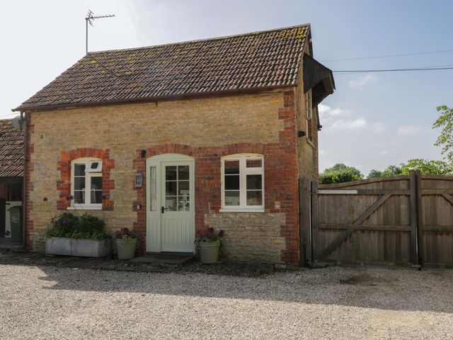 An outdoor view of a stone building with a door and windows at Granary Cottage in Lacock
