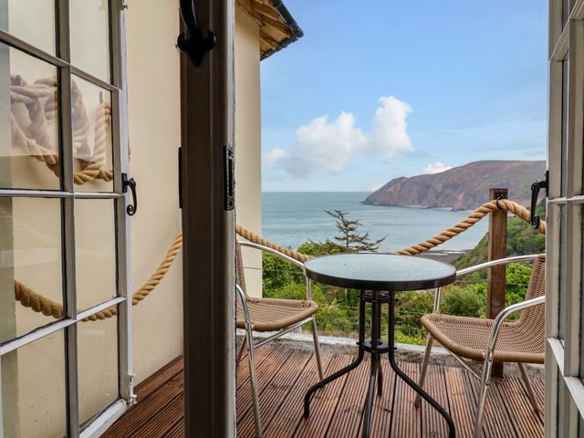 A balcony with a table and two chairs overlooking the sea at Baywatch (St. David's View) Lynton