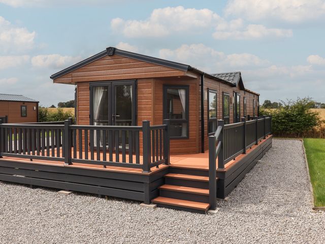 A wooden cabin with a deck and steps at Meadows Park 2 Great Hatfield near Hornsea