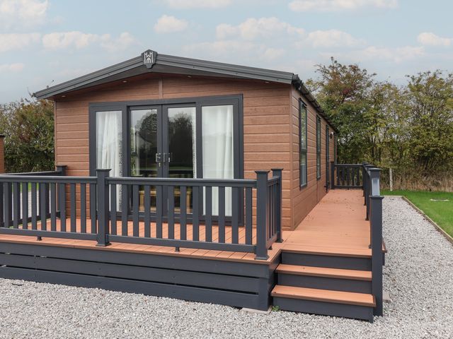 A wooden cabin with a deck and steps at Meadows Park 2 Great Hatfield near Hornsea
