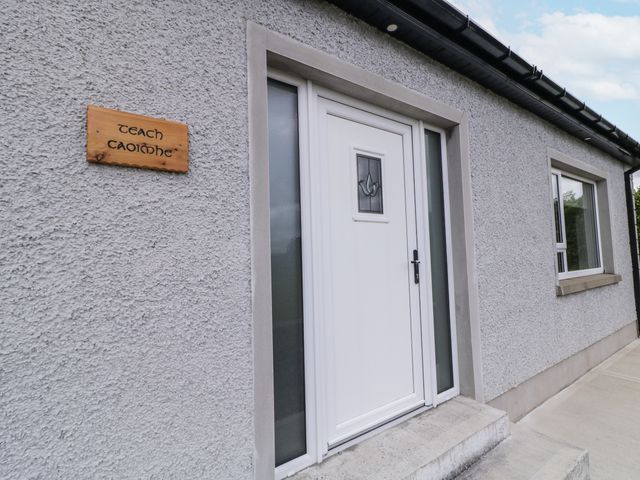 An entrance with a white door and a wooden sign at Teach Caoimhe in Falcarragh
