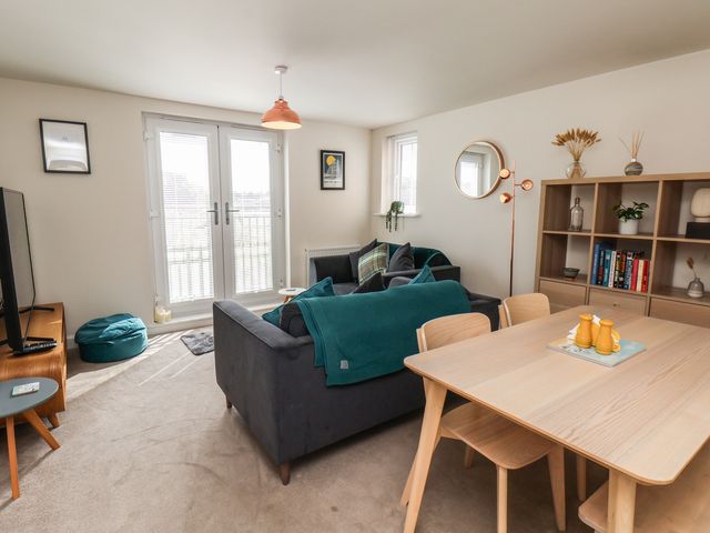 A living room with a sofa, dining table, and television at Larpool Retreat in Whitby
