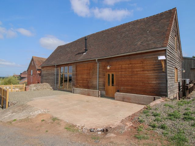 A wooden building with large windows and parking space at Crook Barn in Tenbury Wells