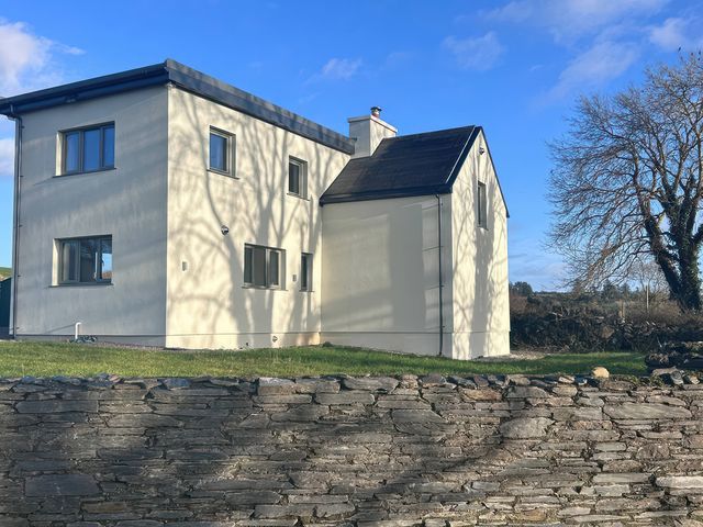 A house with windows and a stone wall at Knocknanuss in 