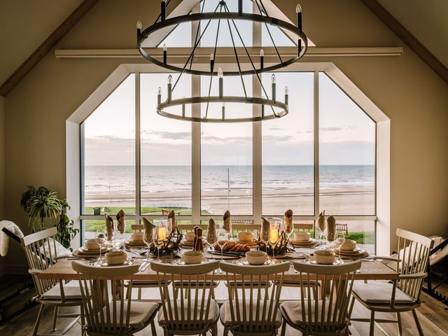 A dining room with a large table and chairs overlooking the ocean at Calm Waters Luxury Beach House in Bridlington