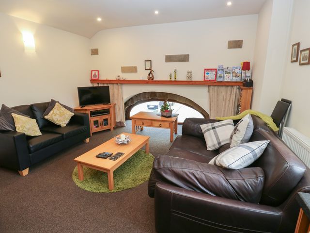 A living room with a television and wooden table at Green Route Apartment