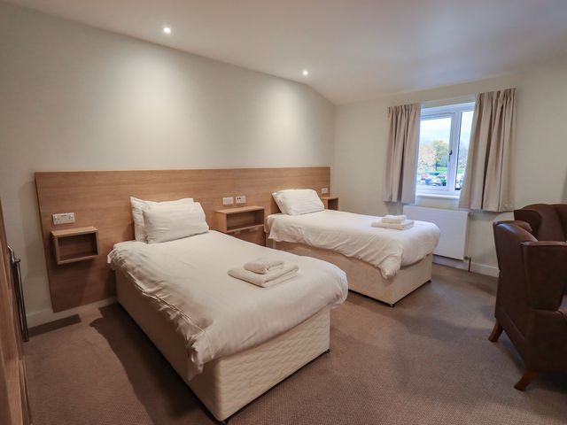 A bedroom with two single beds and a chair at Railway Retreat at Eamont Park Penrith