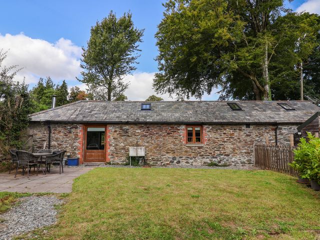 An outdoor view of a stone cottage with a patio at The Coach House in Tavistock