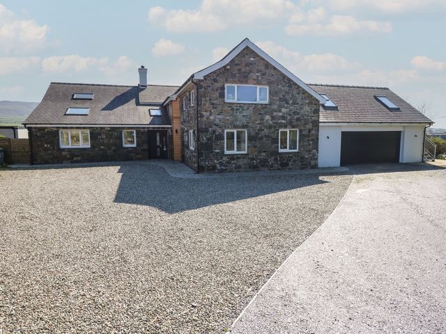 A house with a garage and gravel driveway at Criw Bryncroes near Sarn Meyllteyrn