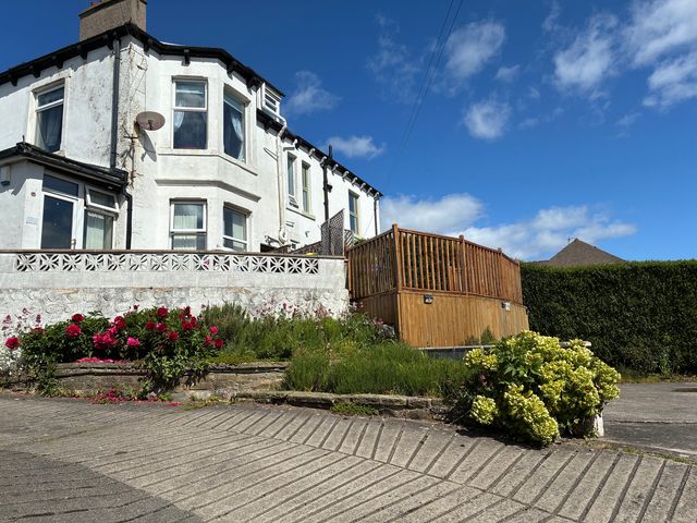 A house with a decking area and flower bed at Ferncliffe in Morecambe