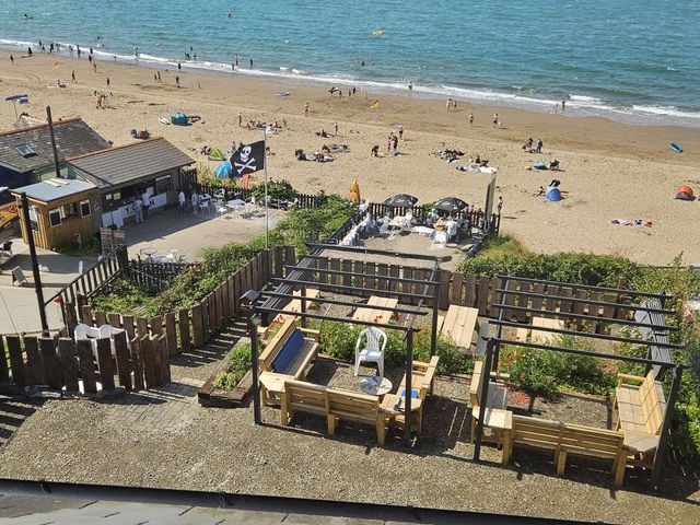 A beach scene with sun umbrellas and seating at Awel Deg in Cardigan