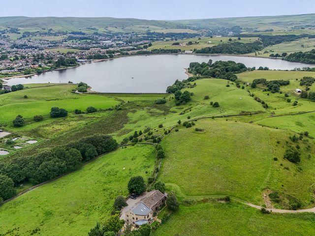 An aerial view of a lake surrounded by fields and hills at Bib Knowl Farm in Littleborough
