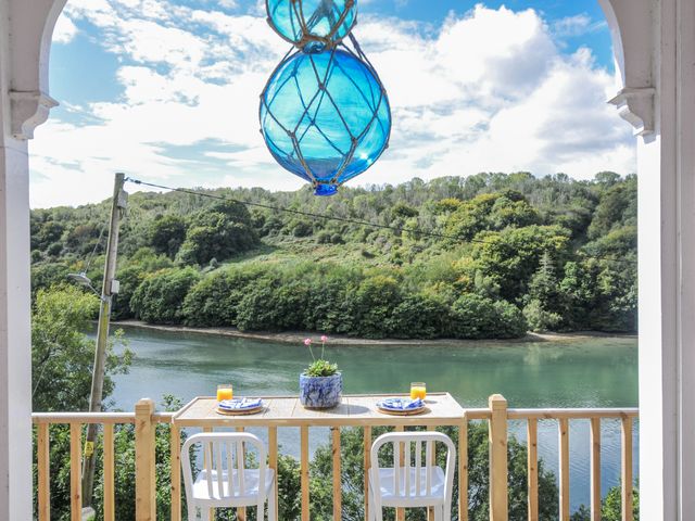 An outdoor balcony with a table and chairs overlooking a river at Mayhurst Looe