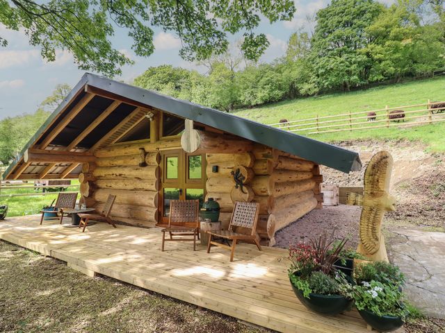 A log cabin with chairs and flower pots at Owl Valley Cabin in Bwlch-y-Ddar near Llanfyllin