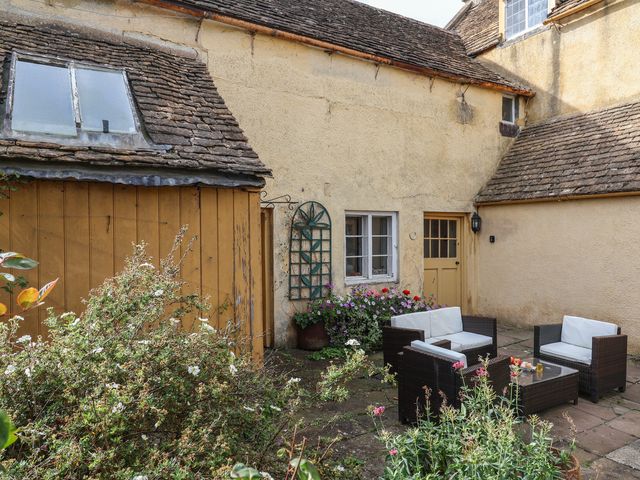 An outdoor seating area with plants and a door at Badminton Farm Cottage