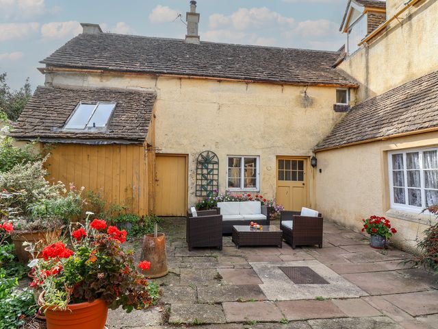 An outdoor seating area with a table and planters at Badminton Farm Cottage