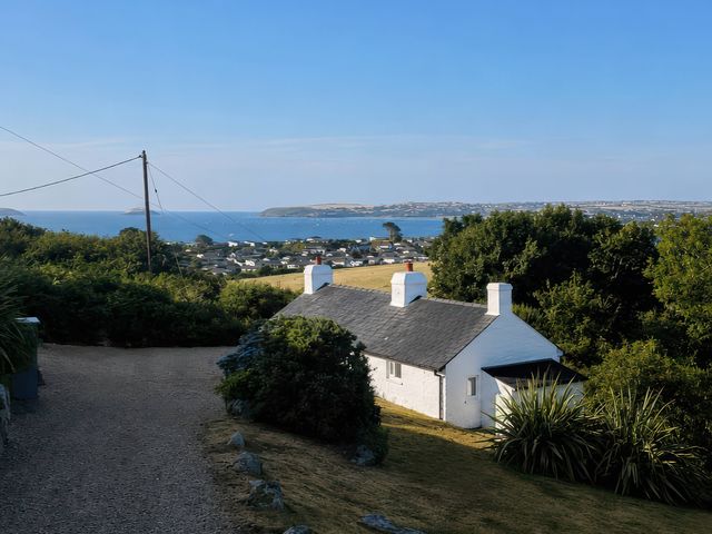 A view of a house with a sea and landscape in the background at Garreg Fawr Llanbedrog