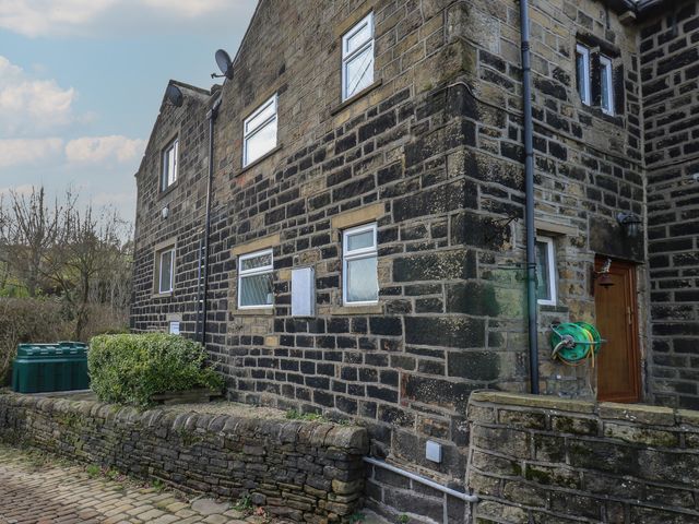 An exterior view of a stone building with windows and a door at 11 Hollin Well Cottage in Sowerby Bridge