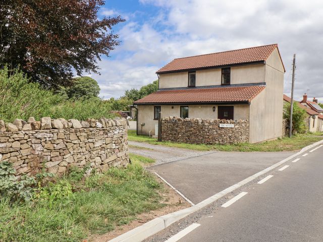 A house with a stone wall and road at The Miners Cottage in Wells
