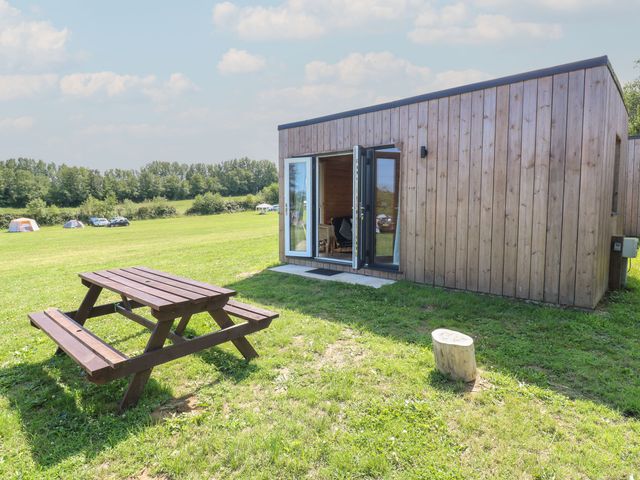 A wooden cabin with a picnic table outside at Bluebell Lodge in Hastings