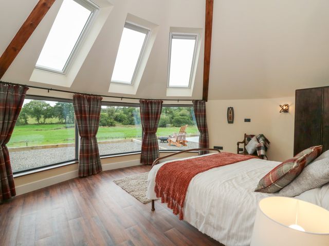 A bedroom with a bed and large windows at Y Cwlwm in Lampeter