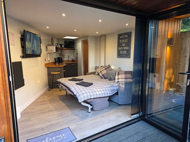 A studio with a bed, sofa, kitchenette, and television at The Chill Garden Room in Shepton Mallet