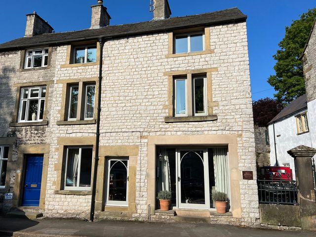 An exterior view of a stone building with windows and a door at Billy Whiskey's in Tideswell