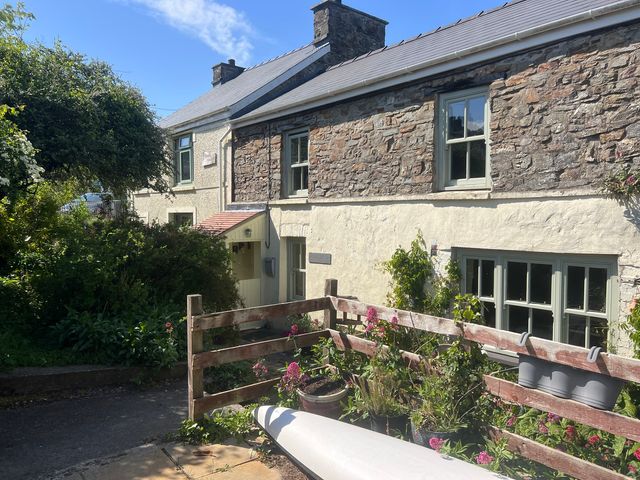 An outdoor view of a stone house with a garden at Penally Mews St Dogmaels