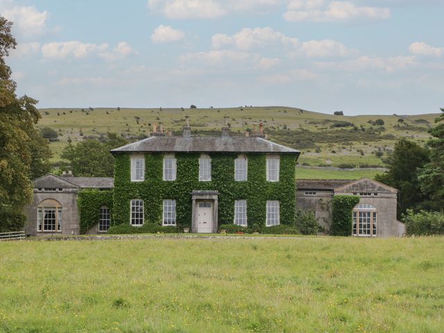 A house with greenery on the facade and surrounding landscape at Huntsman's Cottage in Cartmel