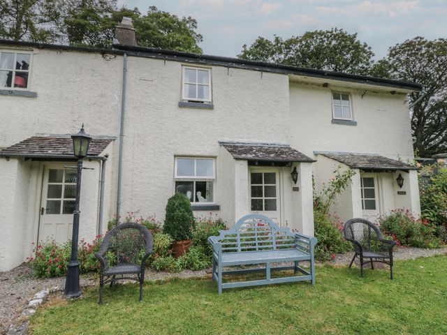 An outdoor view of a cottage with a bench and lantern at The Gameskeepers Cottage in Cartmel