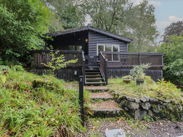 A cabin with steps and a deck at Moon Cottage in White Cross Bay Holiday Park near Troutbeck Bridge