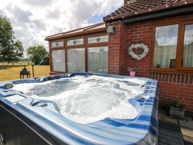 A hot tub outside with a brick wall and window at Pentre Country Studio near Chirk