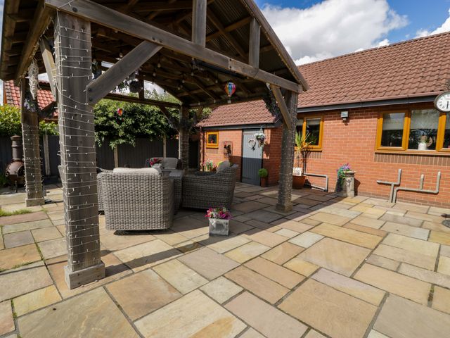 An outdoor patio area with wicker chairs and potted plants at Pentre Country Studio near Chirk