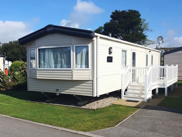 A static caravan with steps and decking at Par Sands Holiday Park - Par