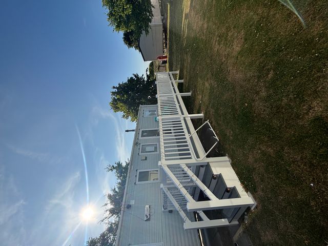 A house with a deck and railing in a grassy area
