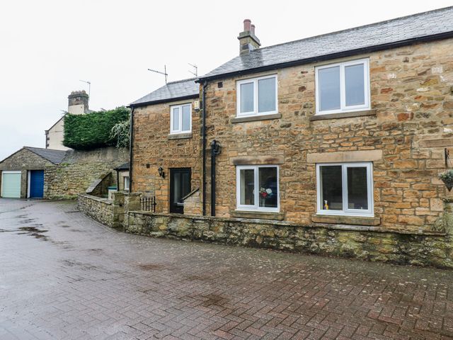 An outdoor view of a stone house with a garage door at 1 Kyles Yard Barnard Castle