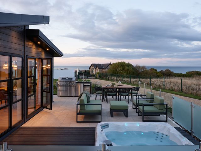 An outdoor patio with seating and a hot tub at Costal Lodge at Seaham Hall, Seaham